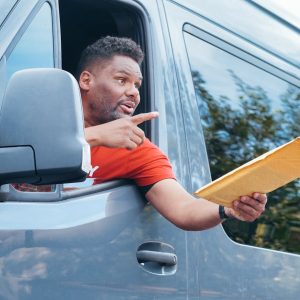 Courier in a van delivering a package through the window on a sunny day.